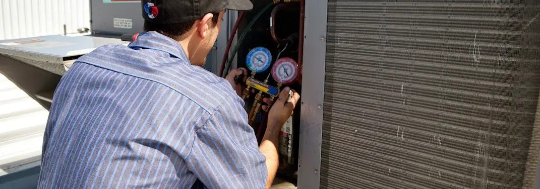 HVAC technician servicing a condenser unit in Inwood